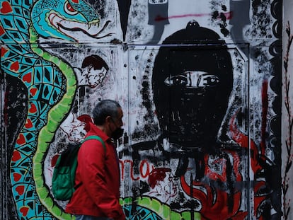 Una persona pasa frente a un grafiti alusivo al Escuadrón Zapatista "La Extemporánea" en Ciudad de México.