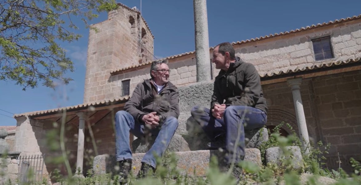 Óscar, a la izquierda, charla con el hematólogo Abelardo Bárez a los pies de la iglesia de San Sebastián, en San García de Ingelmos (Ávila).