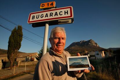 BUGARACH, FRANCE - NOVEMBER 24: The mayor of Bugarach, Jean Pierre Delord, poses with a postcard showing "Ufo" in front of the village. Some are claiming the village of Bugarach will be the only surviving settlement following a devastating apocalypse in December 2012, on November 24, 2011 in Bugarach, France. Although free publicity has boosted the housing market in the village, the Mayor is concerned about the worldwide publicity and the increased volume of people it might attract to the village and it's mountain, Pic de Bugarach.  (Photo by Patrick Aventurier/Getty Images)