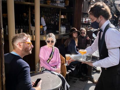 Um garçom atende clientes em um bar de Londres, em 12 de abril.