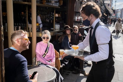 Um garçom atende clientes em um bar de Londres, em 12 de abril.