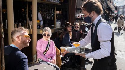 Um garçom atende clientes em um bar de Londres, em 12 de abril.