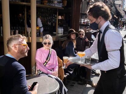 Un camarero atiende a unos clientes en un bar de Londres el pasado 12 de abril.