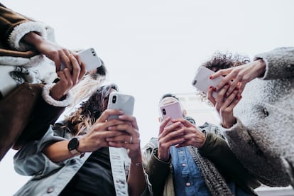 Un grupo de amigos consulta sus teléfonos móviles en la calle.