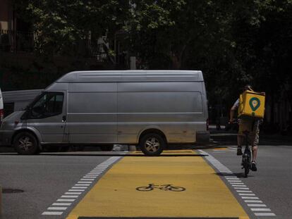 Un repartidor de Glovo y una furgoneta en el nuevo carril bici de Pau Claris.