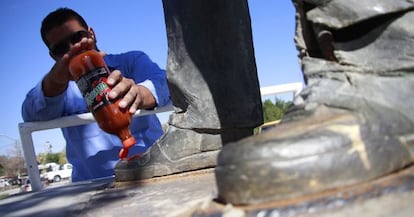 Un empleado limpia con salsa los pies de una estatua.