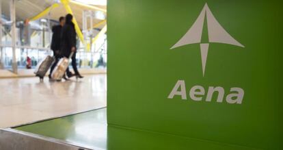 Dos pasajeros pasan ante un expositor de Aena en el aeropuerto madrile&ntilde;o de Barajas. / Reuters