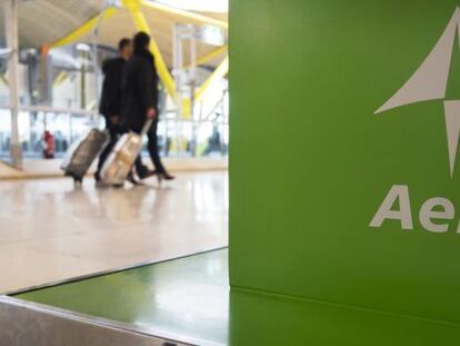 Dos pasajeros pasan ante un expositor de Aena en el aeropuerto madrile&ntilde;o de Barajas. / Reuters