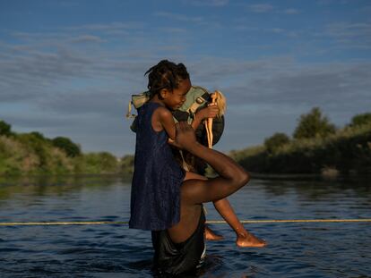 Un hombre haitiano con su hija a hombros cruza el Río Bravo entre Del Río (Texas) y Ciudad Acuña (México), el 22 de septiembre de 2021.