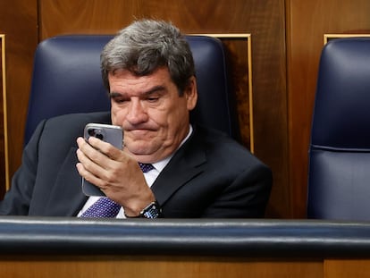 El ministro de Inclusión, Seguridad Social y Migraciones, José Luis Escrivá, consulta su móvil en junio de 2022 en el Congreso de los Diputados.