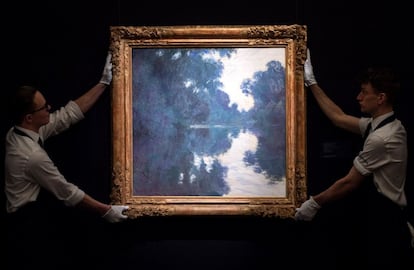 Dos empleados de Sotheby's colocan la obra del artista galo Claude Monet 'Mañana en el Sena, cerca de Giverny' (1897) durante la presentación de la subasta que prepara la casa de subastas Contemporáneo, Impresionismo y Arte Moderno en Londres (Reino Unido).