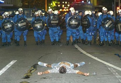 Un militante antiglobalización, tirado en el suelo frente al cordón policial en una calle de Ginebra.