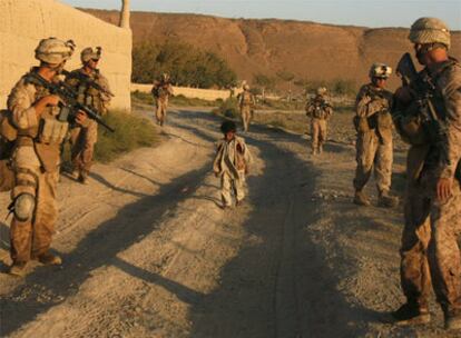 Un niño afgano camina entre <i>marines</i> estadounidenses que realizan una patrulla en la provincia de Helmand (sur).