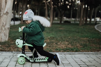 Un niño monta en su patinete por el parque