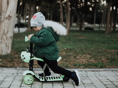 Un niño monta en su patinete por el parque