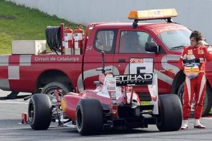 Fernando Alonso junto a su F-10 averiado, ayer en Montmeló.