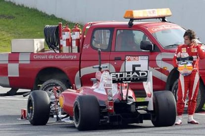 Fernando Alonso junto a su F-10 averiado, ayer en Montmeló.