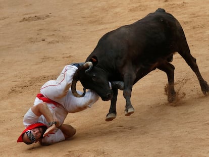 Un corredor es embestido por una vaquilla al final del tercer encierro de San Fermín.