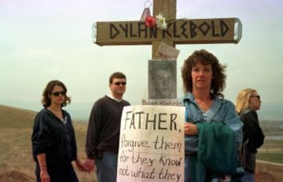 Gente visitando la zona donde se levantó un homenaje a las víctimas de la masacre de Columbine, en Littleton, Colorado. En la imagen, una cruz con la foto y el nombre de Dylan Klebold y una pancarta donde se lee: "Señor, perdónalos porque no saben lo que hacen" (Jesus).