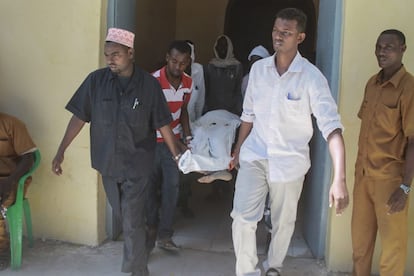 Un grupo de hombres traslada a la víctima de un atentado de Al Shabab en Mogadiscio este jueves.