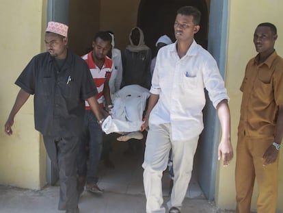 Un grupo de hombres traslada a la v&iacute;ctima de un atentado de Al Shabab en Mogadiscio este jueves. 