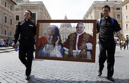 Los papas Juan Pablo II (1920-2005) y Juan XXIII (1881-1963) serán canonizados el 27 de abril y se convertirán así en los otros dos pontífices proclamados santos en los últimos 100 años junto con Pío X. En la imagen, dos sacerdotes caminan por la Plaza de San Pedro con cuadro collage de los dos papas que serán canonizados el 27 de abril de 2014.
