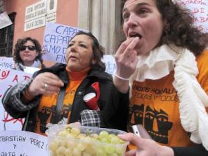 Trabajadoras de servicios sociales de la Diputación de Granada se toman las uvas con doce horas de antelación, justo al mediodía, para protestar por los despidos de 24 empleados y pedir que la asistencia social se mantenga como prioridad en la Administración provincial.