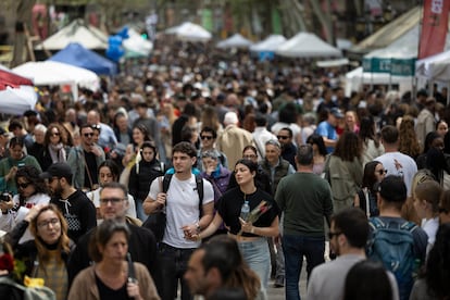 Una pareja pasea cogidos de la mano y con una rosa por la concurrida Rambla de Barcelona.