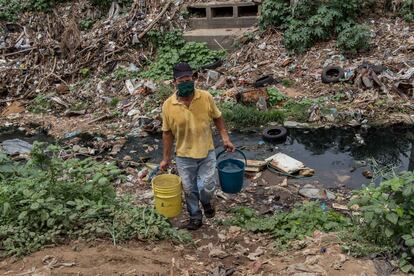 Un hombre recoge agua el lunes 29 de junio de una quebrada contaminada, en Maracaibo (Venezuela).
