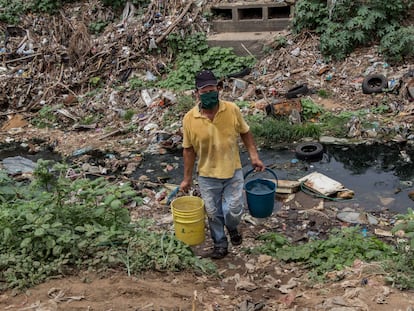 Un hombre recoge agua el lunes 29 de junio de una quebrada contaminada, en Maracaibo (Venezuela).