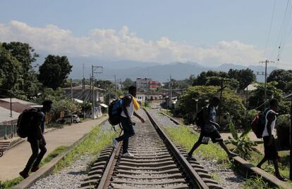 Migrantes haitianos cruzan una vía férrea en el municipio de Huixtla, en el Estado de Chiapas (México).