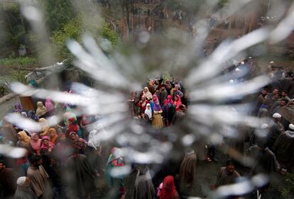 Se ve a la gente a través de un agujero de bala en una ventana de una casa dañada después de un tiroteo entre presuntos militantes y las fuerzas de seguridad indias en Turkewangam, en el distrito de Shopian de Cachemira.