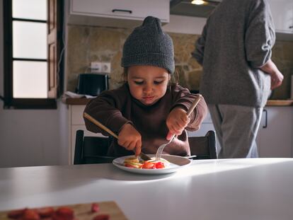 Un niño come fruta en la cocina.