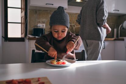 Un niño come fruta en la cocina.