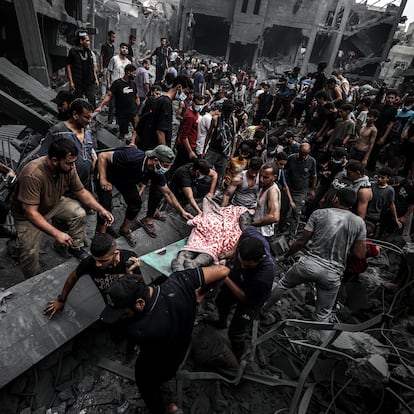 GAZA CITY, GAZA - OCTOBER 27: (EDITORS NOTE: Image depicts graphic content) People carry injured and dead Palestinians from the rubbles of buildings as civil defense teams and civilians conduct search and rescue operations after Israeli attacks on Al-Shati refugee camp of Gaza City, Gaza on October 27, 2023 as Israeli attacks continue on the 21st day on Gaza. As a result of the Israeli attacks, some buildings were completely destroyed, while others were severely damaged. (Photo by Ali Jadallah/Anadolu via Getty Images)