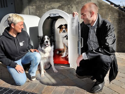 Dos personas muestran una de las casetas de la empresa noruega Den4Dogs para dejar al perro de manera segura en la puerta de un supermercado.