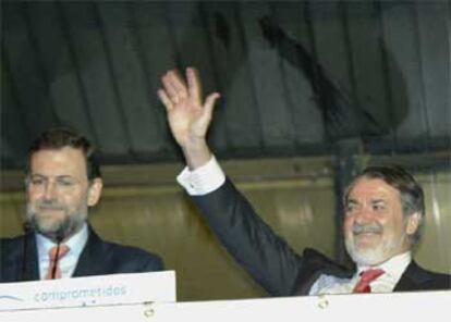 Mariano Rajoy y Jaime Mayor, anoche, saludan y dan las gracias a sus militantes en el balcón de la sede del PP, en la calle de Génova.