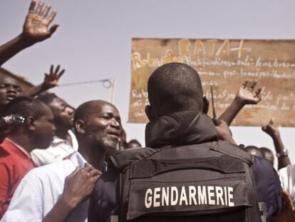 Un miembro de la polic&iacute;a de Burkina Faso corta el acceso de la gente al cementerio donde se lleva a cabo la exhumaci&oacute;n.