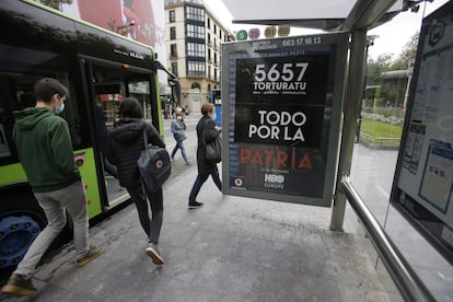 Un cartel contra la tortura colocado en una marquesina de San Sebastián tapa el que promociona la serie 'Patria'.