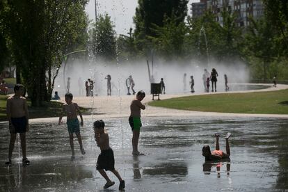 Decenas de niños juegan este viernes en la playa urbana de Madrid Río, una fuente con chorros que surgen del suelo periódicamente.