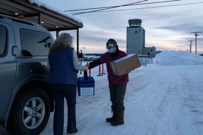 Crystal Stordahl, directora del programa de ayuda de salud comunitaria de Tanana, entrega una hielera que contiene la vacuna contra la covid-19 a la asistente de médicos Jo Miller en Fairbanks, Alaska.