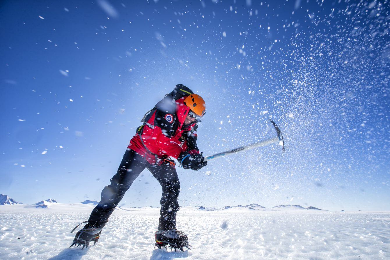 El explorador militar Juan Pablo Muñoz hace un agujero en el hielo con un piolet.