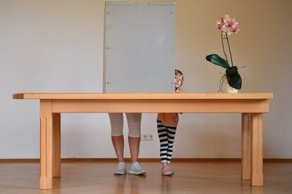 Una niña se asoma mientras su madre vota en un colegio electoral de Wildenberg, Alemania.
