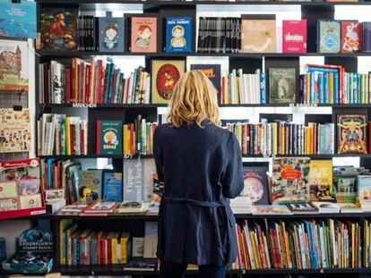 Una mujer observa la estantería de una librería.