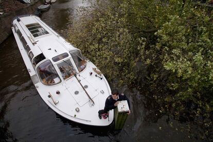 El capitán de un barco de turistas se aferra a un poste para evitar un choque con un árbol caído en un canal en Herengracht, Amsterdam.