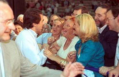 Militantes populares saludan a José María Aznar, ayer, en el mitin de su partido en un polideportivo de Málaga.