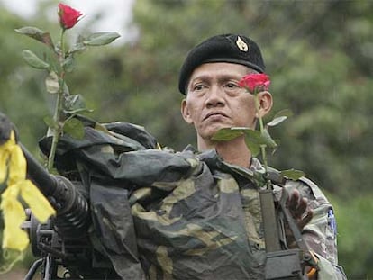 Un soldado decora su ametralladora con dos flores recibidas de la gente y una cinta amarilla de lealtad al rey.