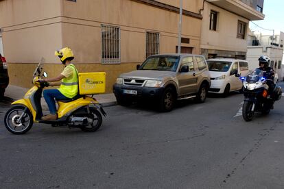 Un agente de la Policía Nacional escolta a uno de los carteros que reparte el voto por correo.