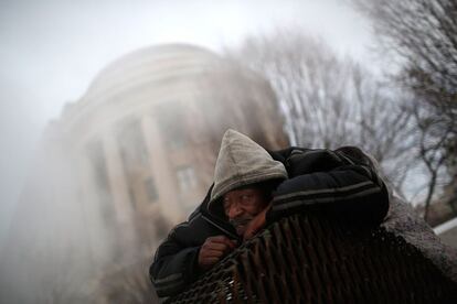 WASHINGTON, DC - FEBRUARY 17: Donnie Prince, who is homeless, tries to stay warm on top of a steam grate outside the Federal Trade Commission on Constitution Avenue February 17, 2015 in Washington, DC. The Washington DC area received 4-6 inches of snow overnight as a winter storm hit large areas of the east coast. Win McNamee/Getty Images/AFP == FOR NEWSPAPERS, INTERNET, TELCOS & TELEVISION USE ONLY ==