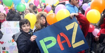 Unos niños portan un cartel por la paz en la suelta de globos de Bilbao.